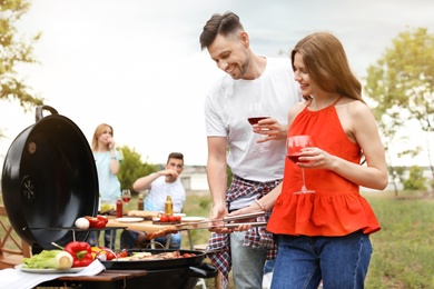 Young people having barbecue with modern grill outdoors