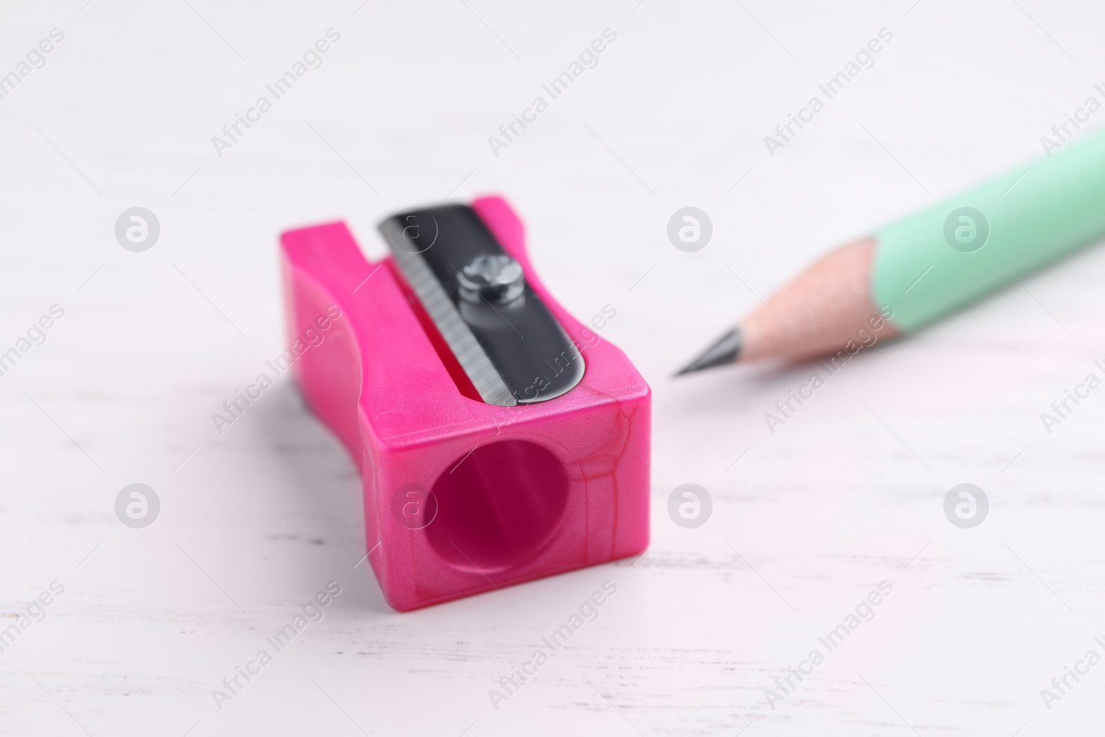 Photo of Pencil and sharpener on white wooden background, closeup