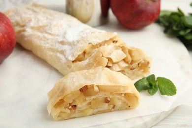 Photo of Delicious apple strudel with almonds and mint on white board, closeup