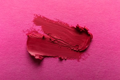 Smears of beautiful lipstick on pink background, top view