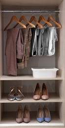 Photo of Collection of stylish clothes and shoes in large wardrobe closet