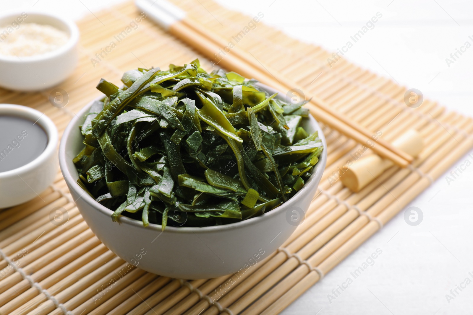 Photo of Fresh laminaria (kelp) seaweed served on white wooden table