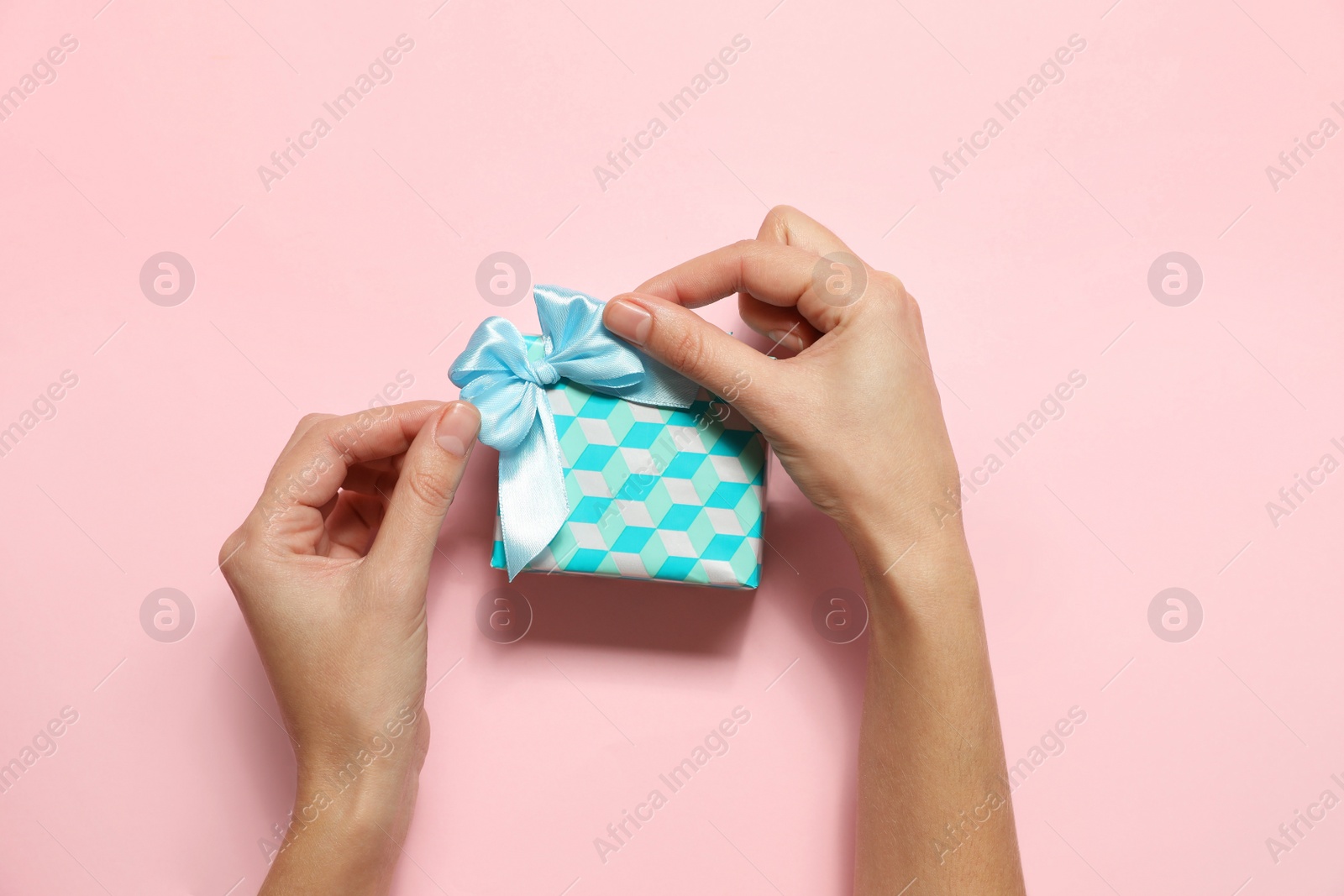 Photo of Woman with Christmas gift on pink background, top view