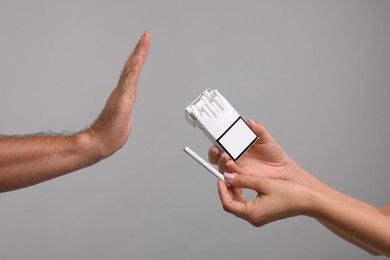 Photo of Stop smoking concept. Man refusing cigarettes on grey background, closeup