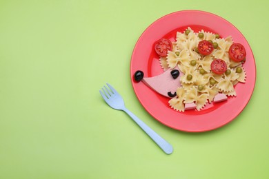 Photo of Creative serving for kids. Plate with cute hedgehog made of delicious pasta, sausages and tomatoes on green table, flat lay. Space for text