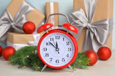 Photo of Alarm clock, fir branches and gifts on table. Christmas countdown