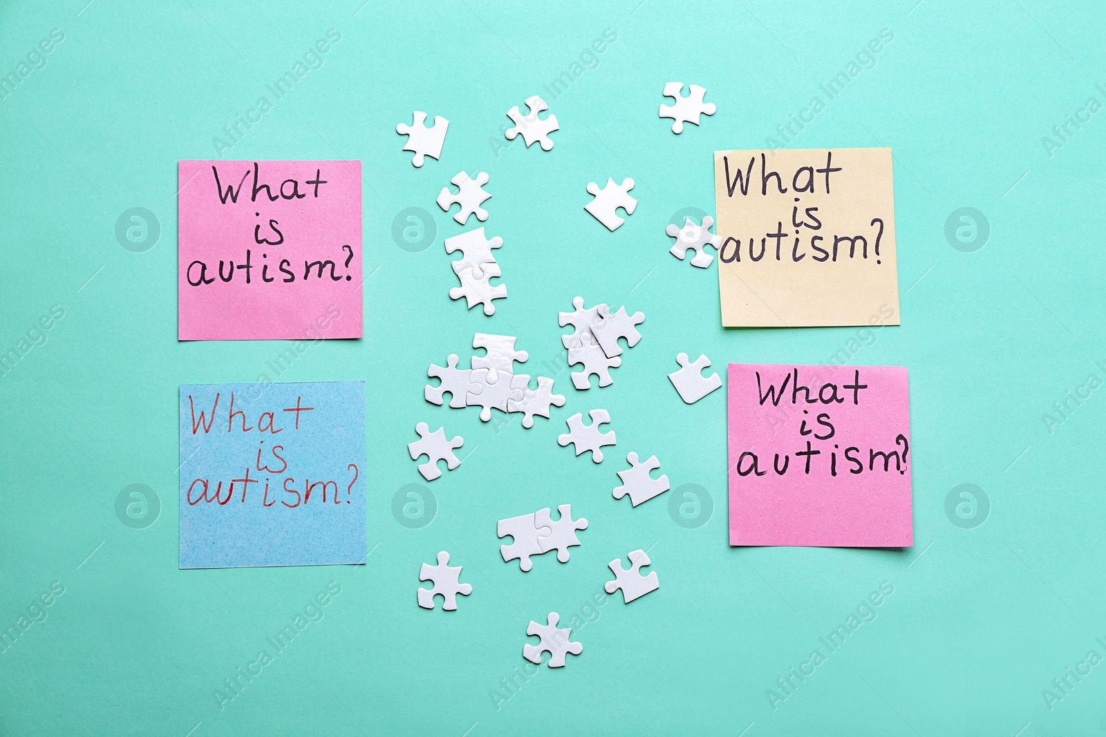 Photo of Sticky notes with phrase "What is autism?" and puzzle pieces on color background, flat lay