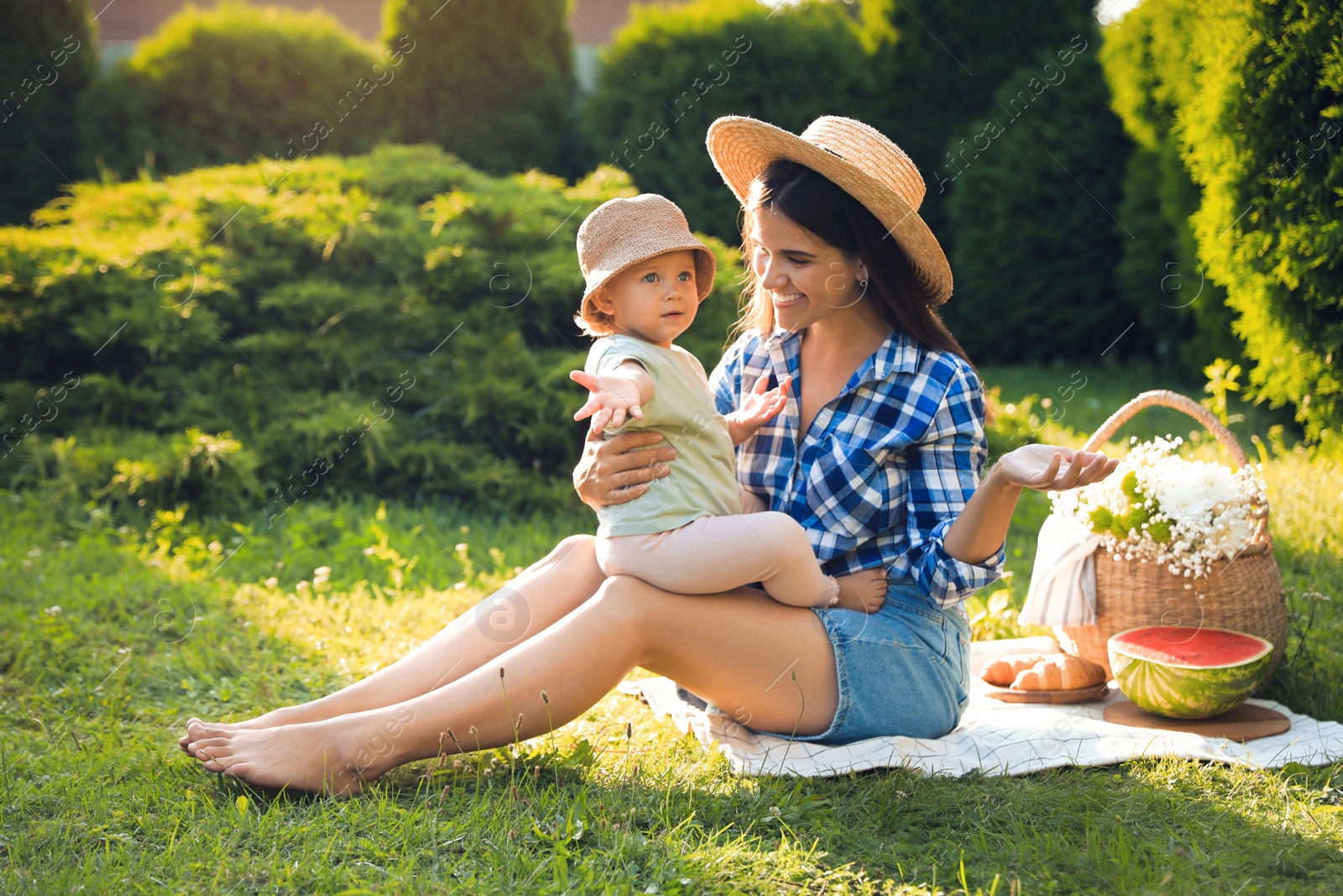 Photo of Mother with her baby daughter having picnic in garden on sunny day