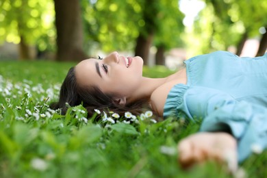 Beautiful woman lying on green grass in park. Spring sunny day