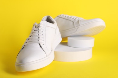 Photo of Pair of stylish white sneakers on yellow background