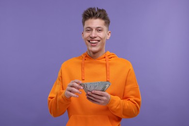 Happy man with money on purple background