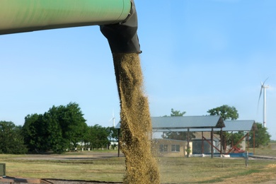 Photo of Modern combine harvester unloading wheat outdoors, closeup view of side pipe. Agriculture industry