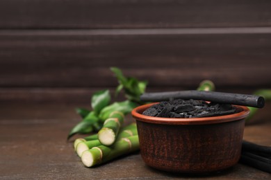 Photo of Fresh bamboo and charcoal on wooden table, space for text