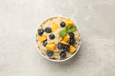 Photo of Tasty quinoa porridge with blueberries and pumpkin in bowl on light grey table, top view