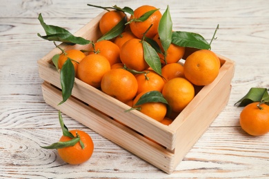 Photo of Fresh ripe tangerines in wooden crate on table