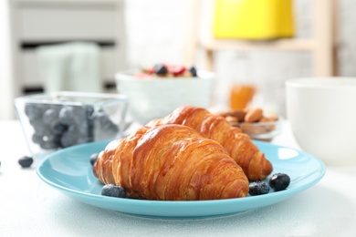 Photo of Delicious breakfast with croissants and berries on white table indoors