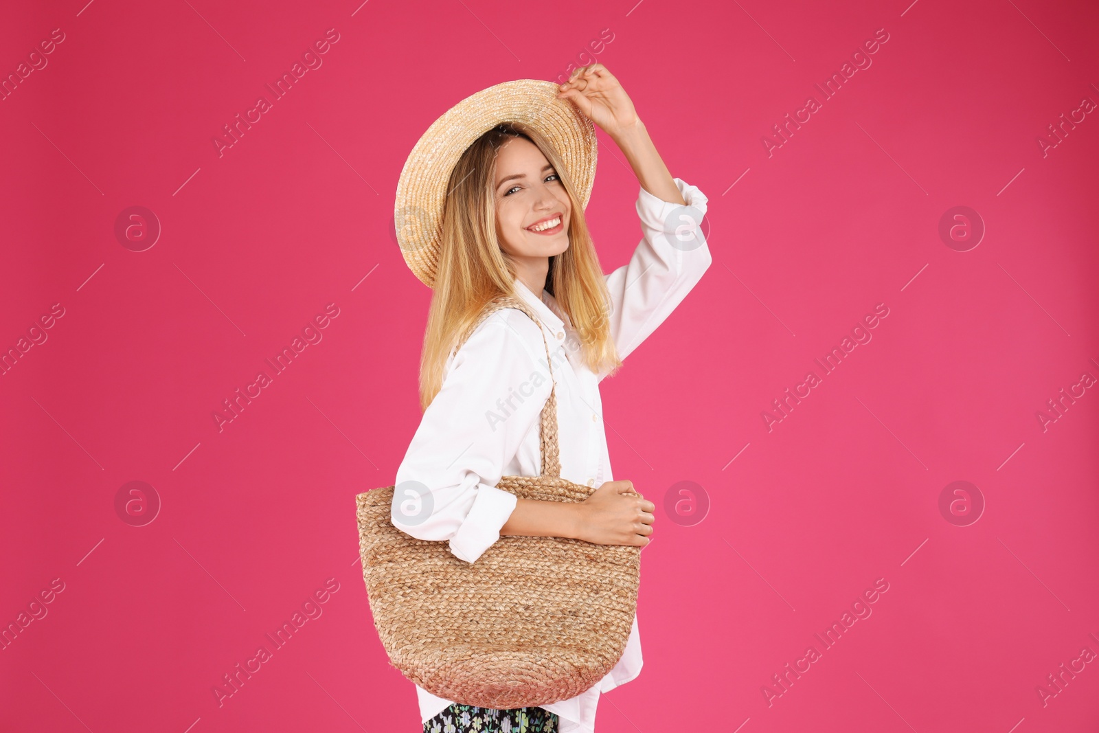 Photo of Beautiful young woman with stylish straw bag on pink background