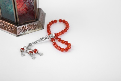 Photo of Muslim lamp and prayer beads on white background. Space for text