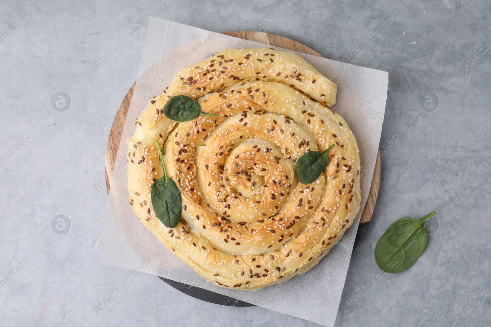 Photo of Delicious puff pastry with spinach on grey table, top view