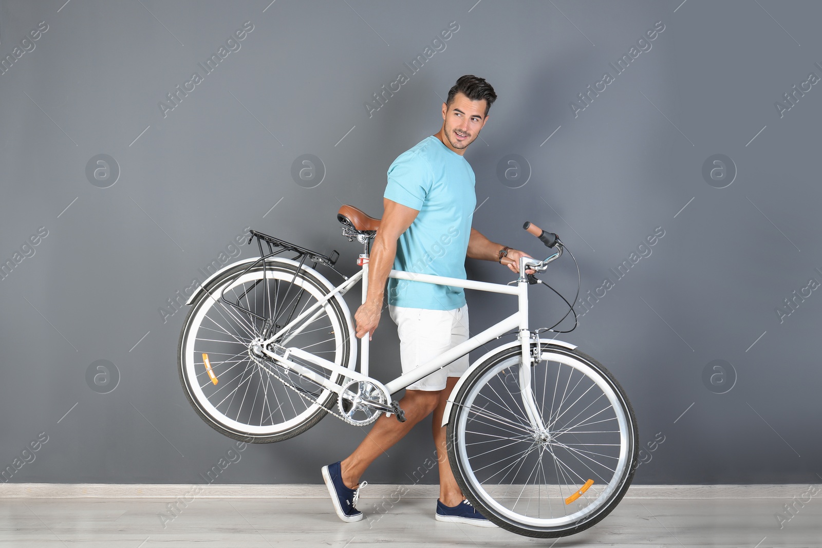 Photo of Handsome young hipster man with bicycle near color wall