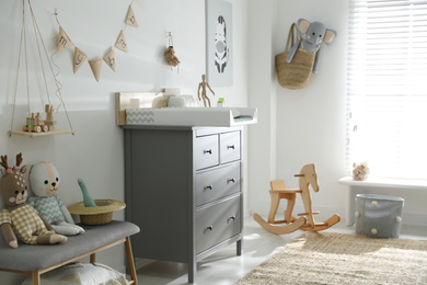 Photo of Beautiful baby room interior with toys and modern changing table