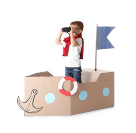 Photo of Cute little boy playing with cardboard ship on white background