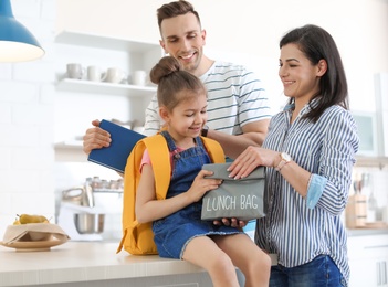 Young parents helping their little child get ready for school at home