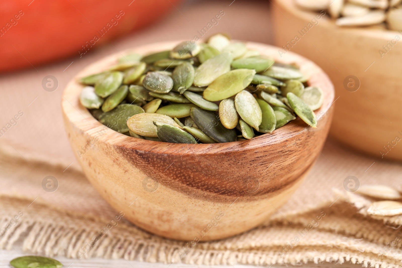 Photo of Wooden bowl with peeled pumpkin seeds on table, closeup