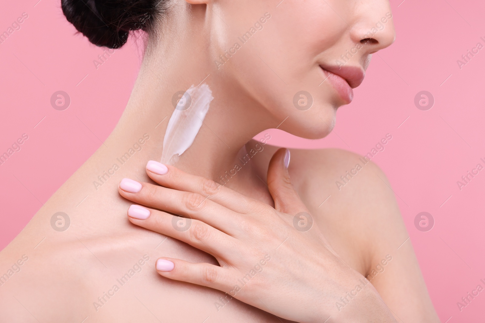 Photo of Woman with smear of body cream on her neck against pink background, closeup