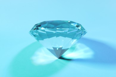Photo of Beautiful dazzling diamond on light blue background, closeup