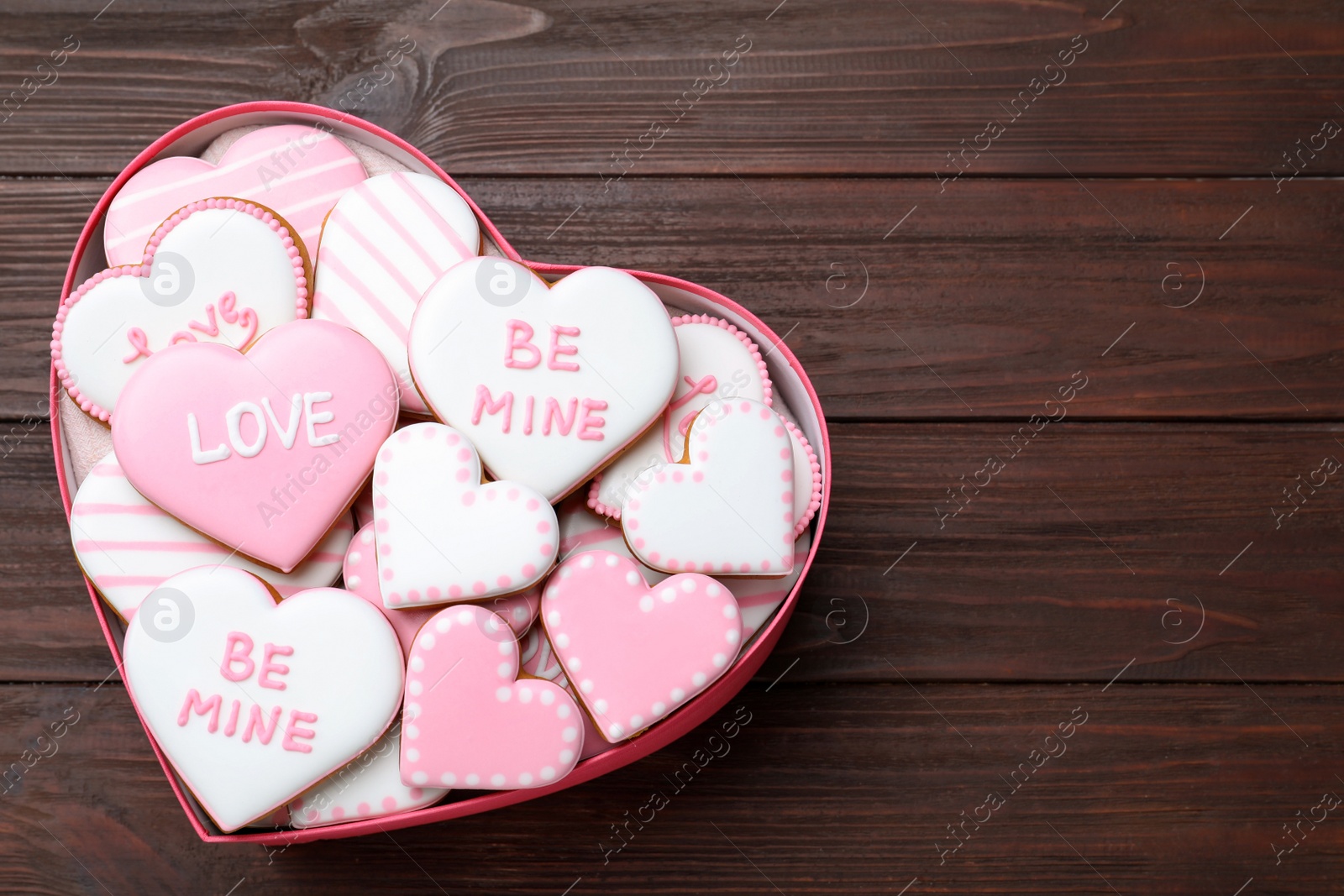 Photo of Valentine's day cookies in heart shaped box on wooden table, top view. Space for text