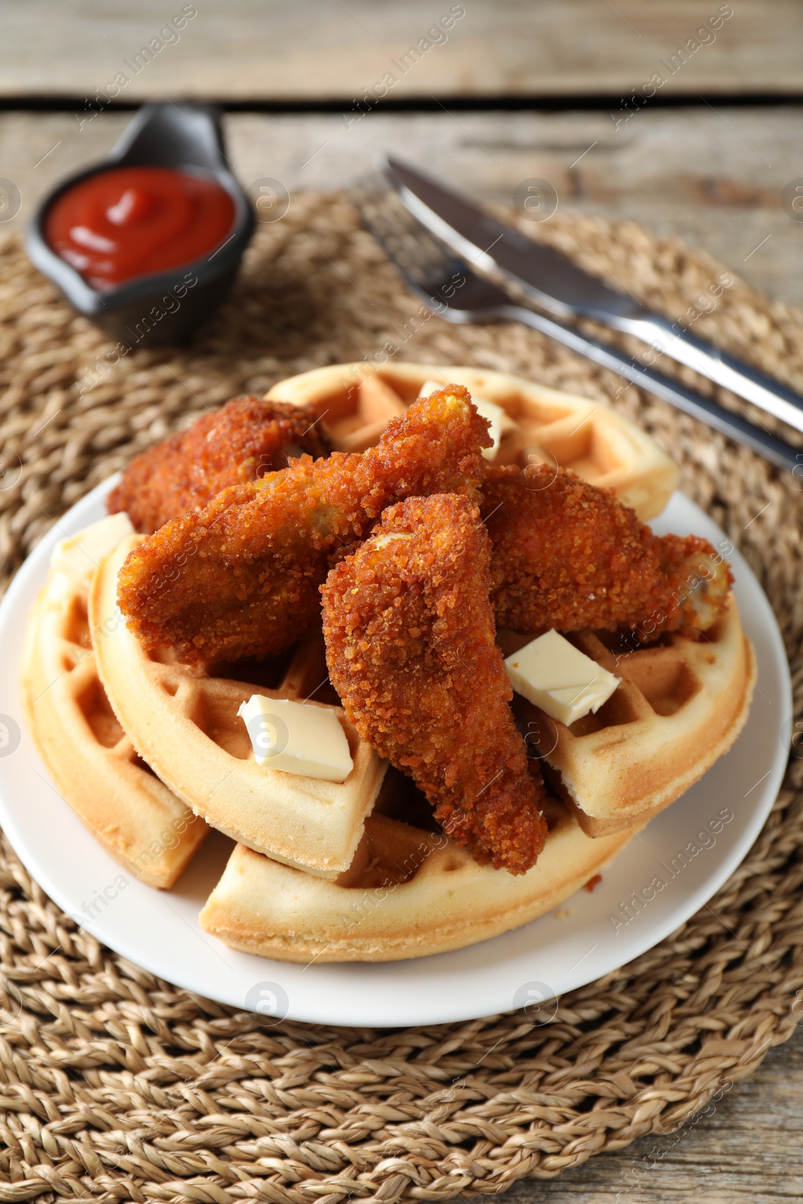Photo of Delicious Belgium waffles served with fried chicken and butter on wooden table, closeup