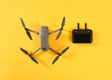 Modern drone with controller on yellow background, flat lay