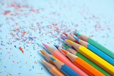 Color pencils and shavings on blue background, closeup