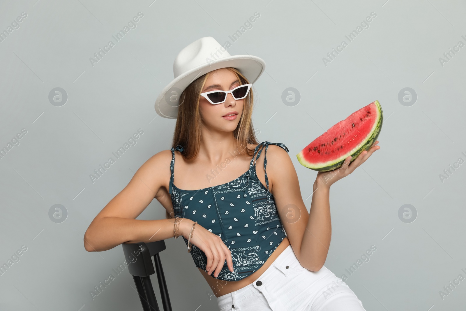 Photo of Beautiful girl on chair with watermelon against grey background