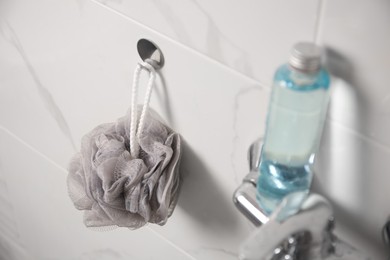 Grey shower puff and bottle of body wash gel in bathroom
