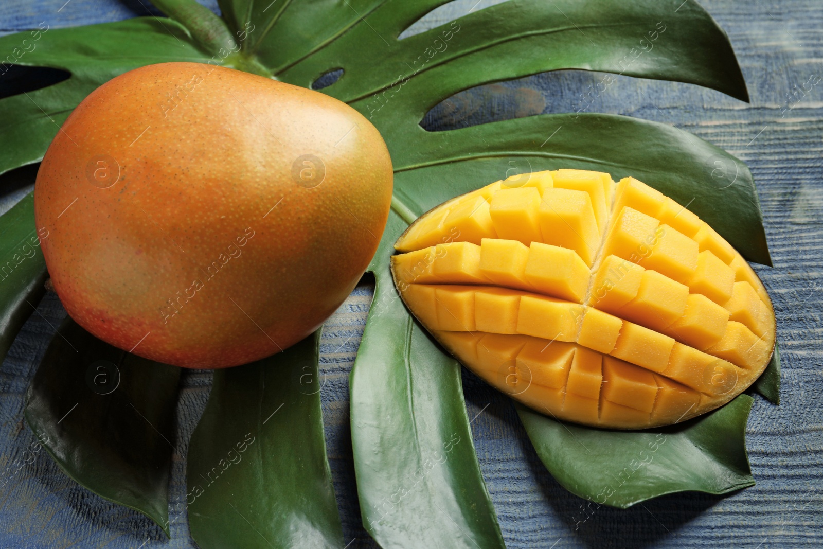 Photo of Mango and tropical leaf on wooden background