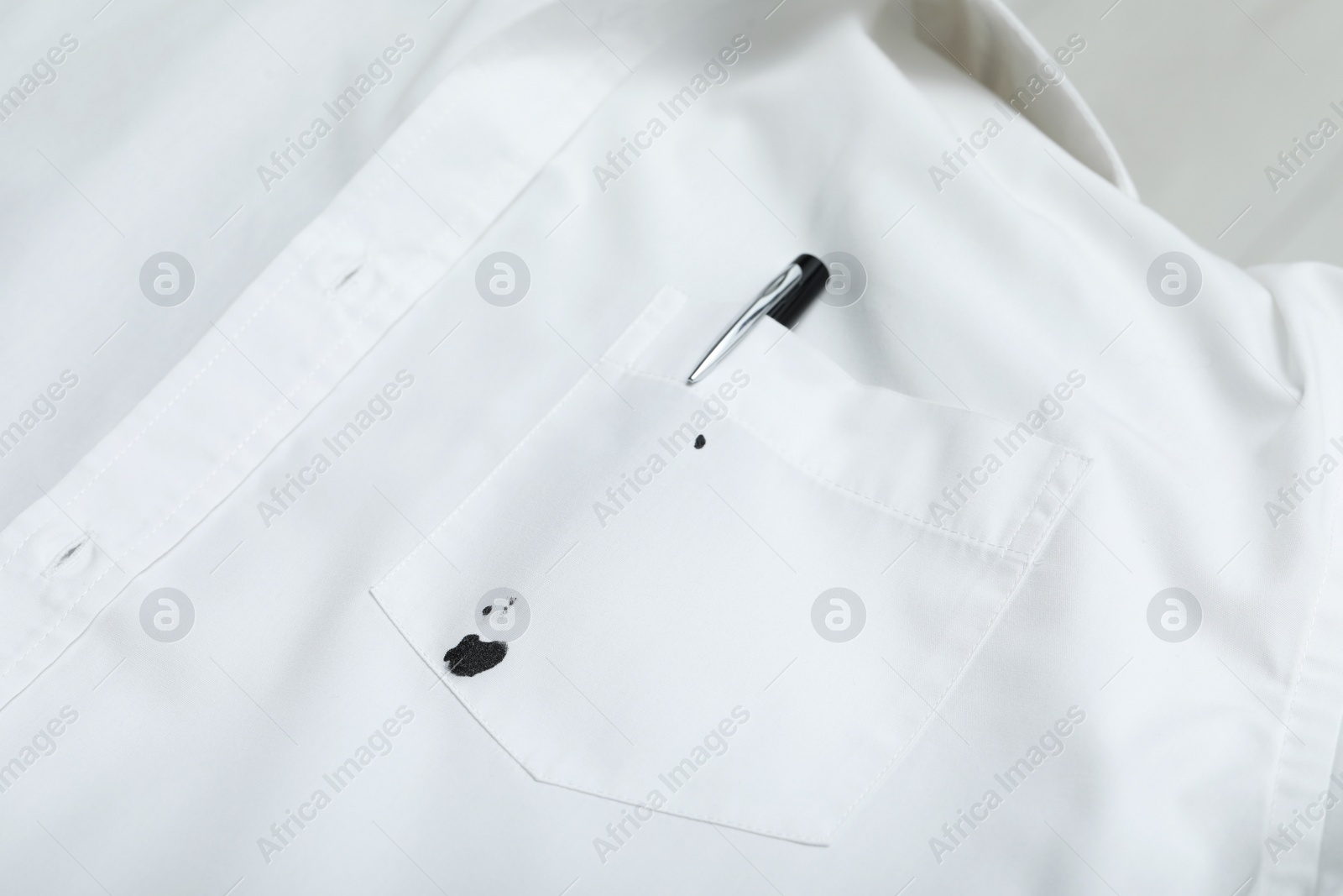 Photo of Pen and stain of black ink on white shirt, closeup