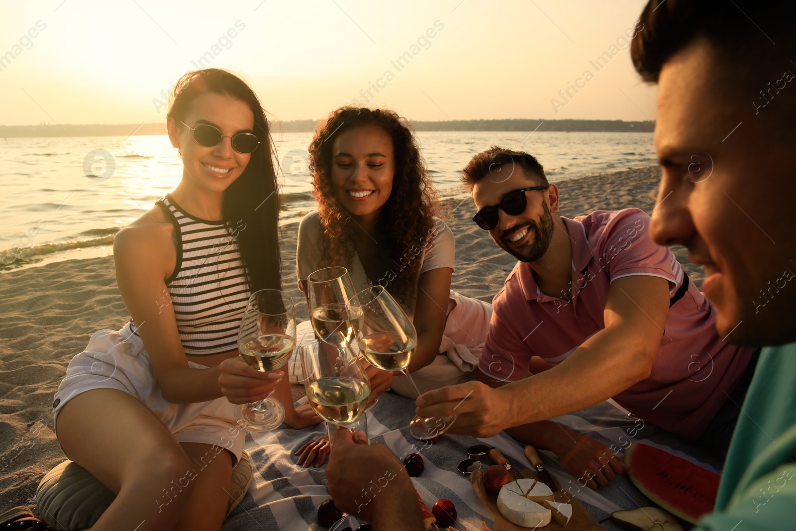 Photo of Group of friends having picnic near river at sunset