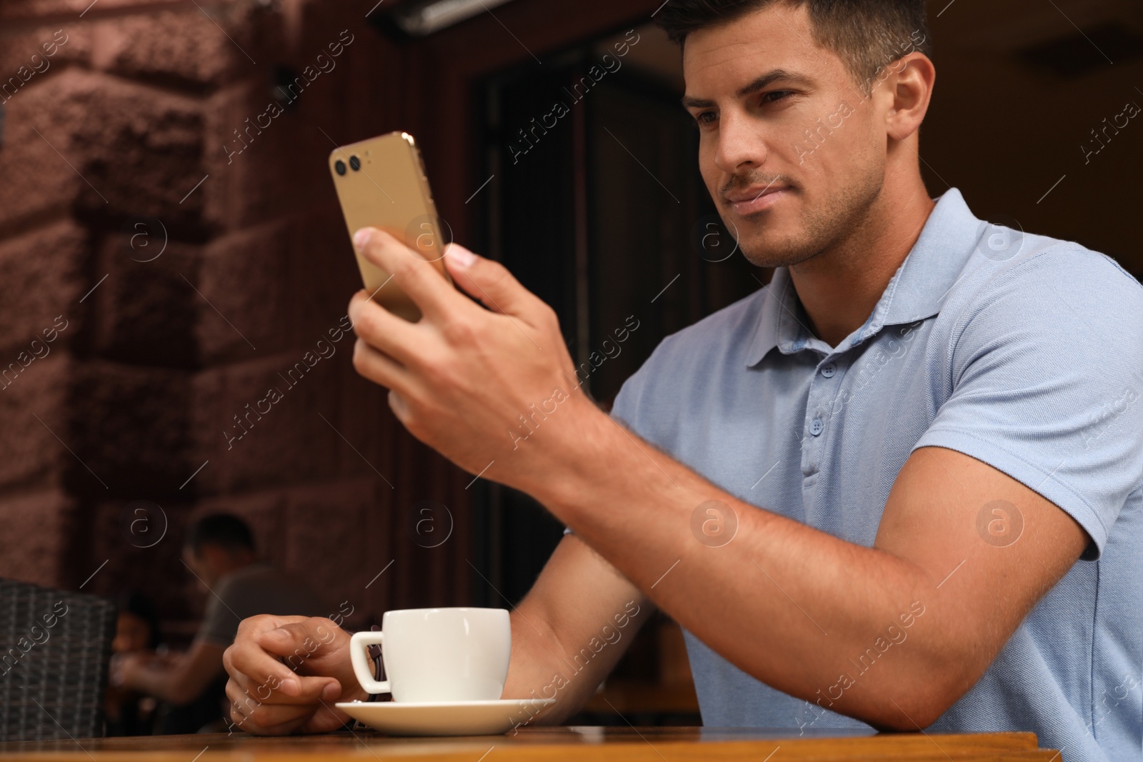 Photo of Man unlocking smartphone with facial scanner in outdoor cafe. Biometric verification