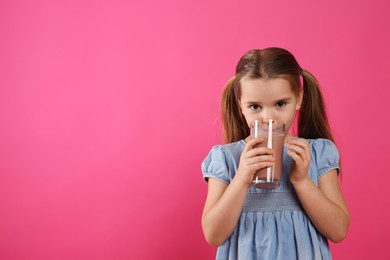 Photo of Cute little child drinking tasty chocolate milk on pink background, space for text