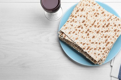 Photo of Stack of matzos and red wine on white wooden table, flat lay. Space for text