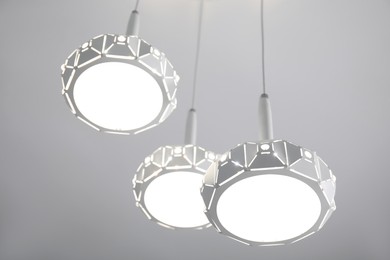 Stylish pendant lamp on white ceiling, low angle view
