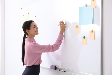 Young teacher writing on whiteboard in classroom