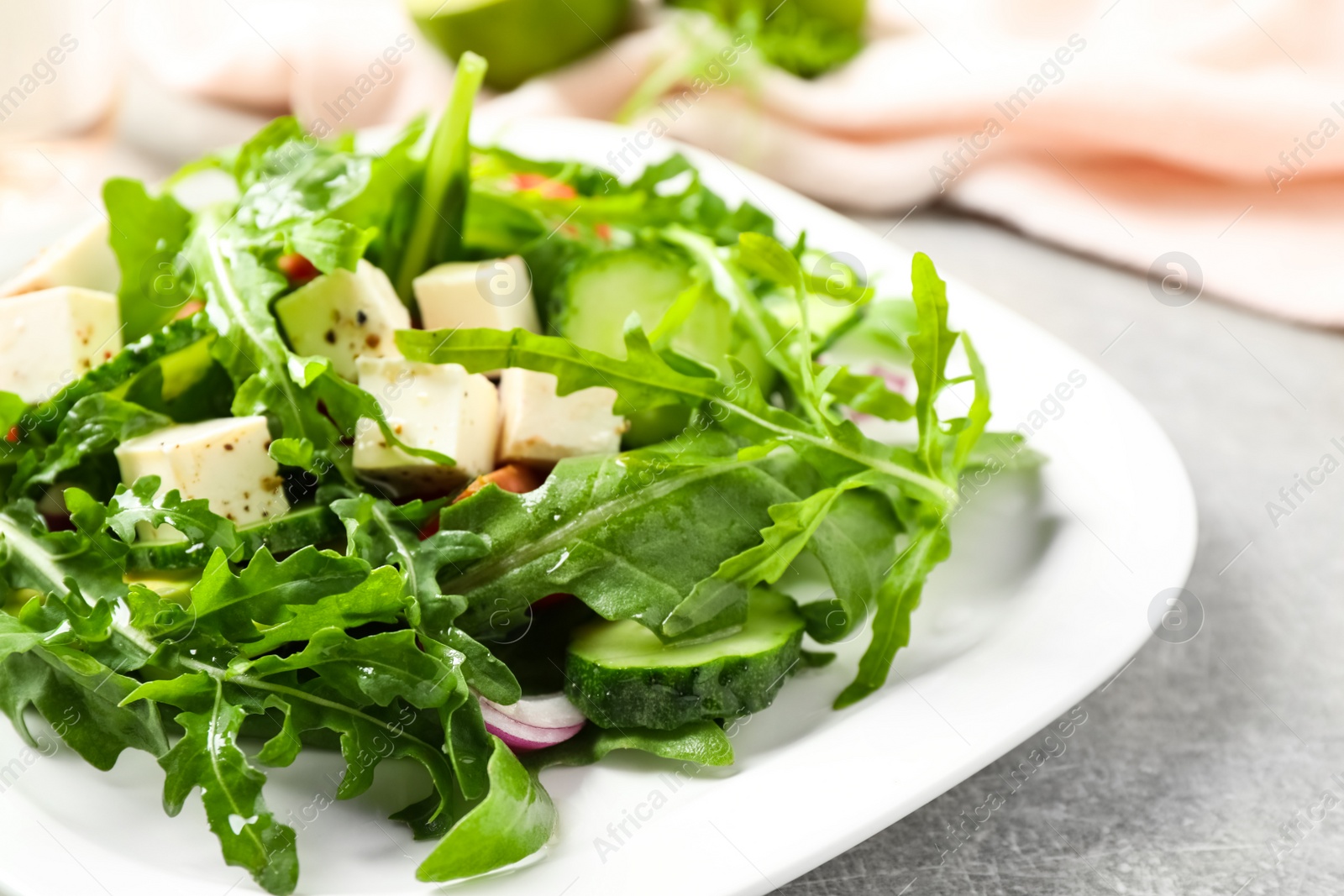 Photo of Delicious salad with feta cheese, arugula and vegetables on grey table, closeup