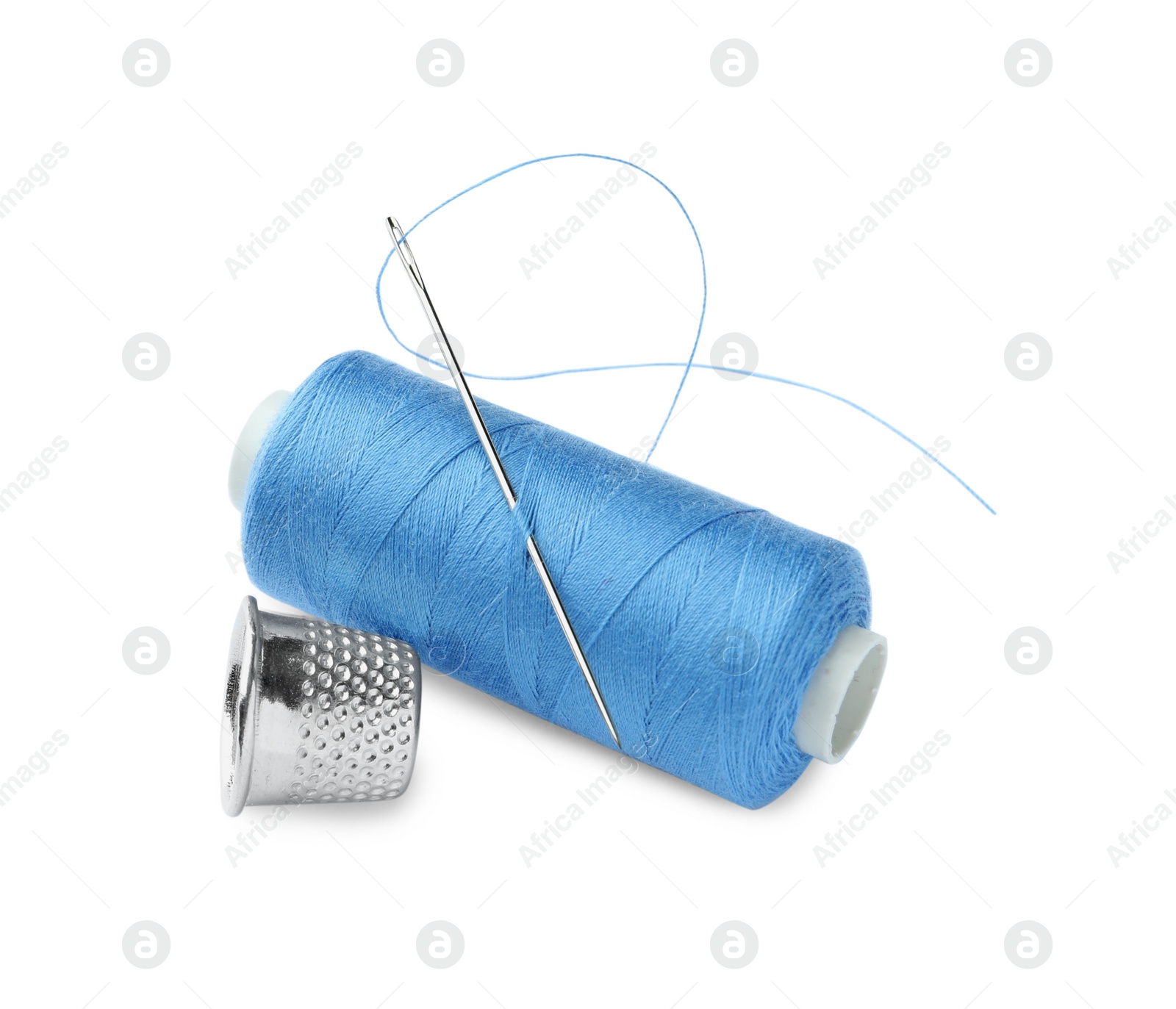 Photo of Spool of light blue sewing thread with needle and thimble on white background