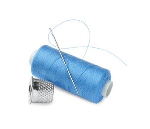 Photo of Spool of light blue sewing thread with needle and thimble on white background