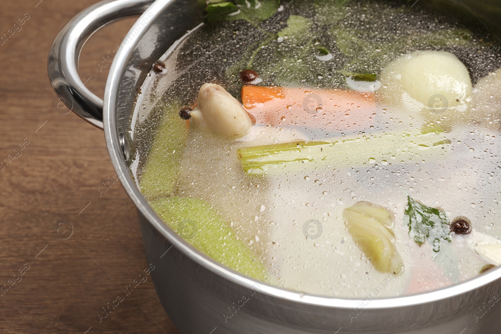 Photo of Pot with tasty bouillon on wooden table, closeup