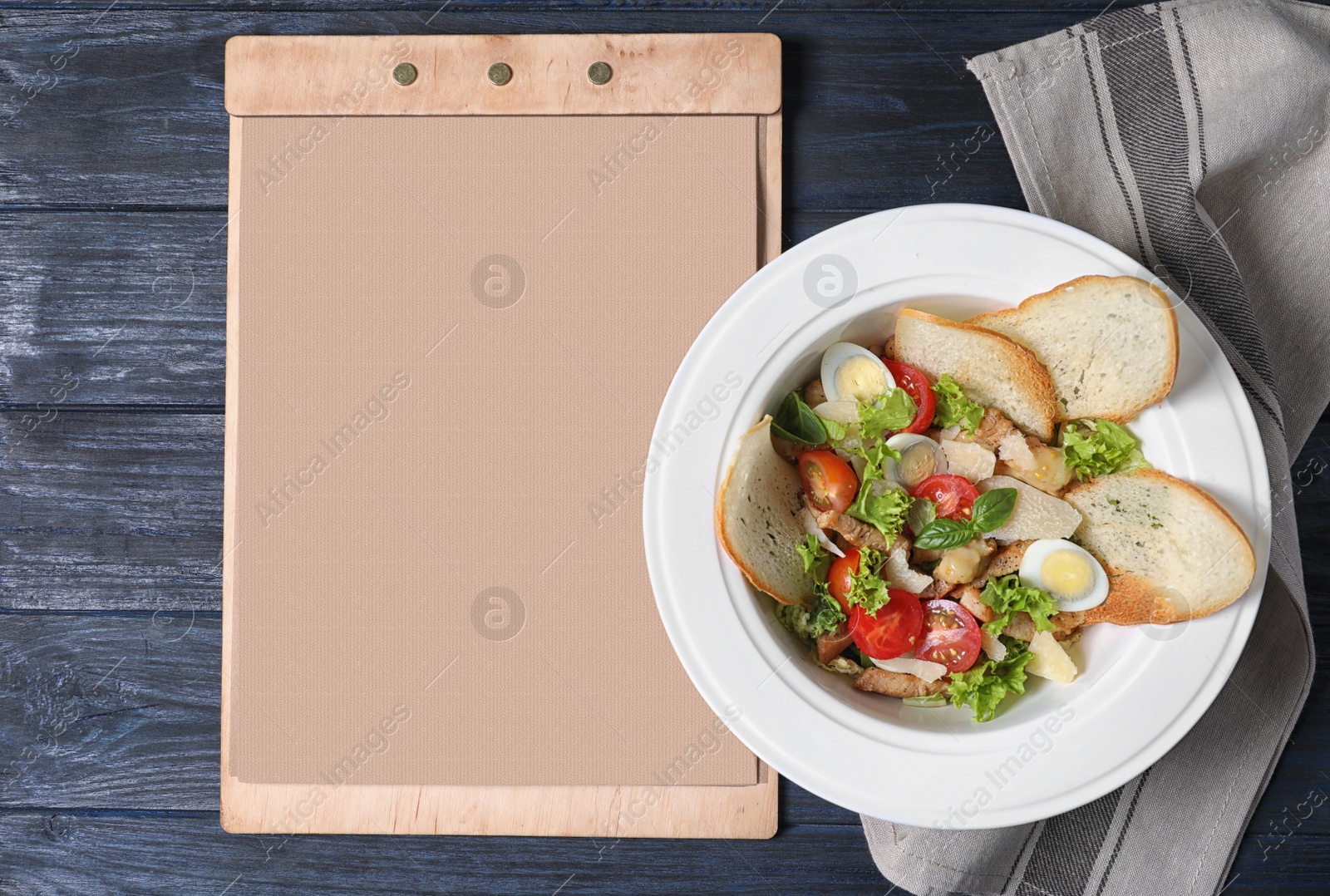 Photo of Plate with delicious fresh salad and menu on table, top view