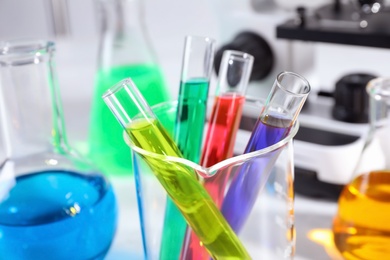 Photo of Different glassware with samples on table in chemistry laboratory, closeup